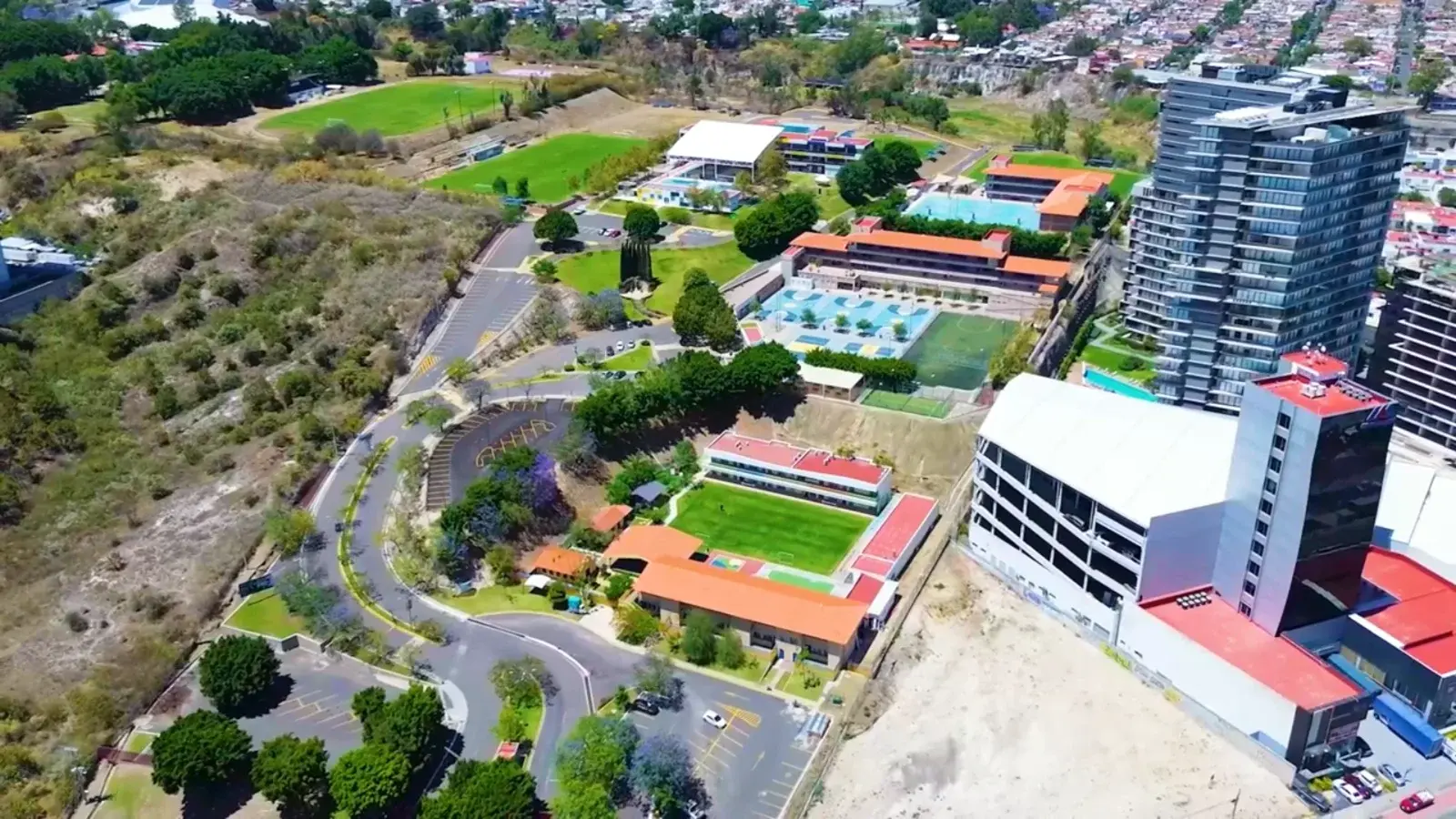 Vista aérea del campus con edificios modernos, áreas verdes, piscinas y canchas deportivas del colegio