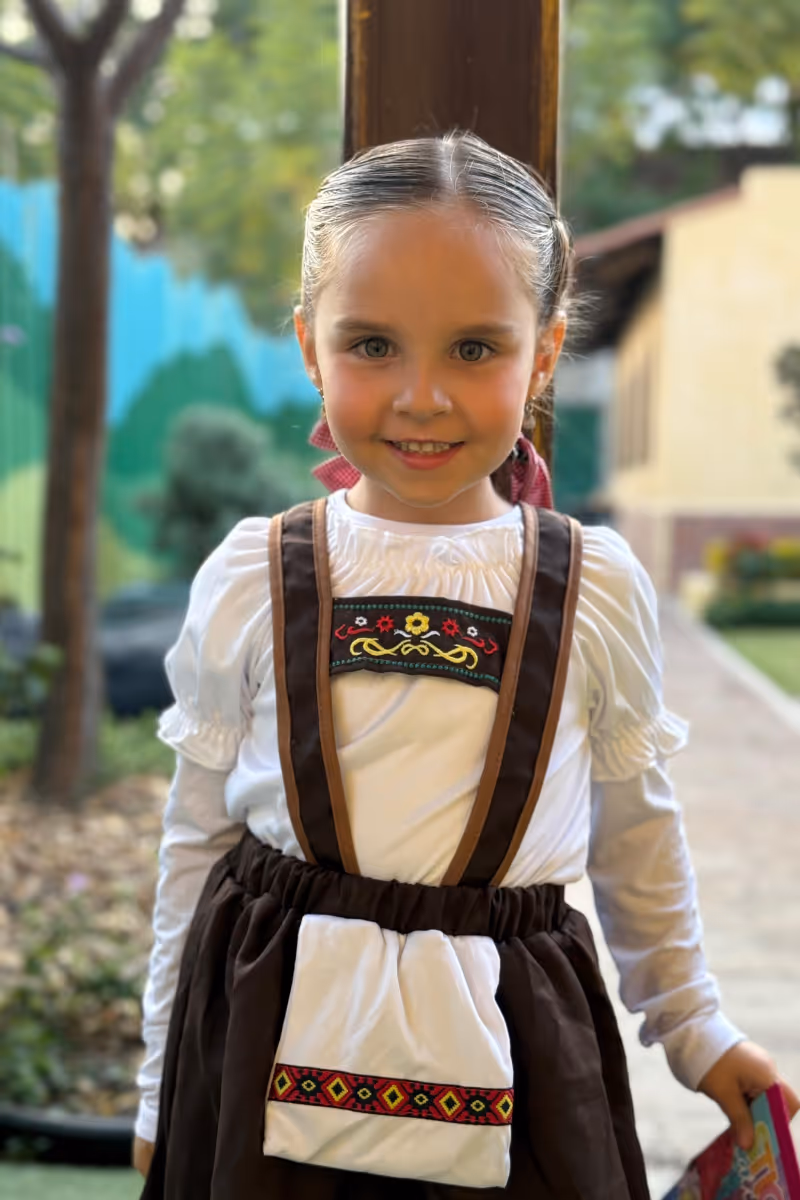 Niños sonrientes sentados en escalones con uniforme escolar deportivo.